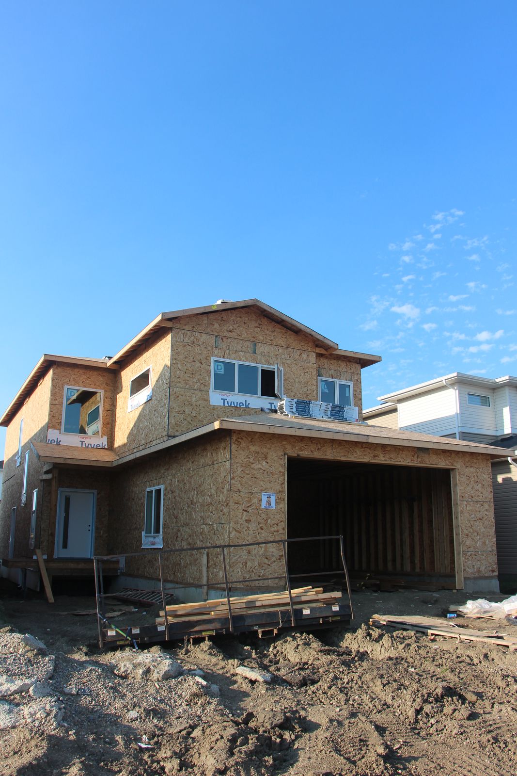 Custom home exterior framing under a clear sky